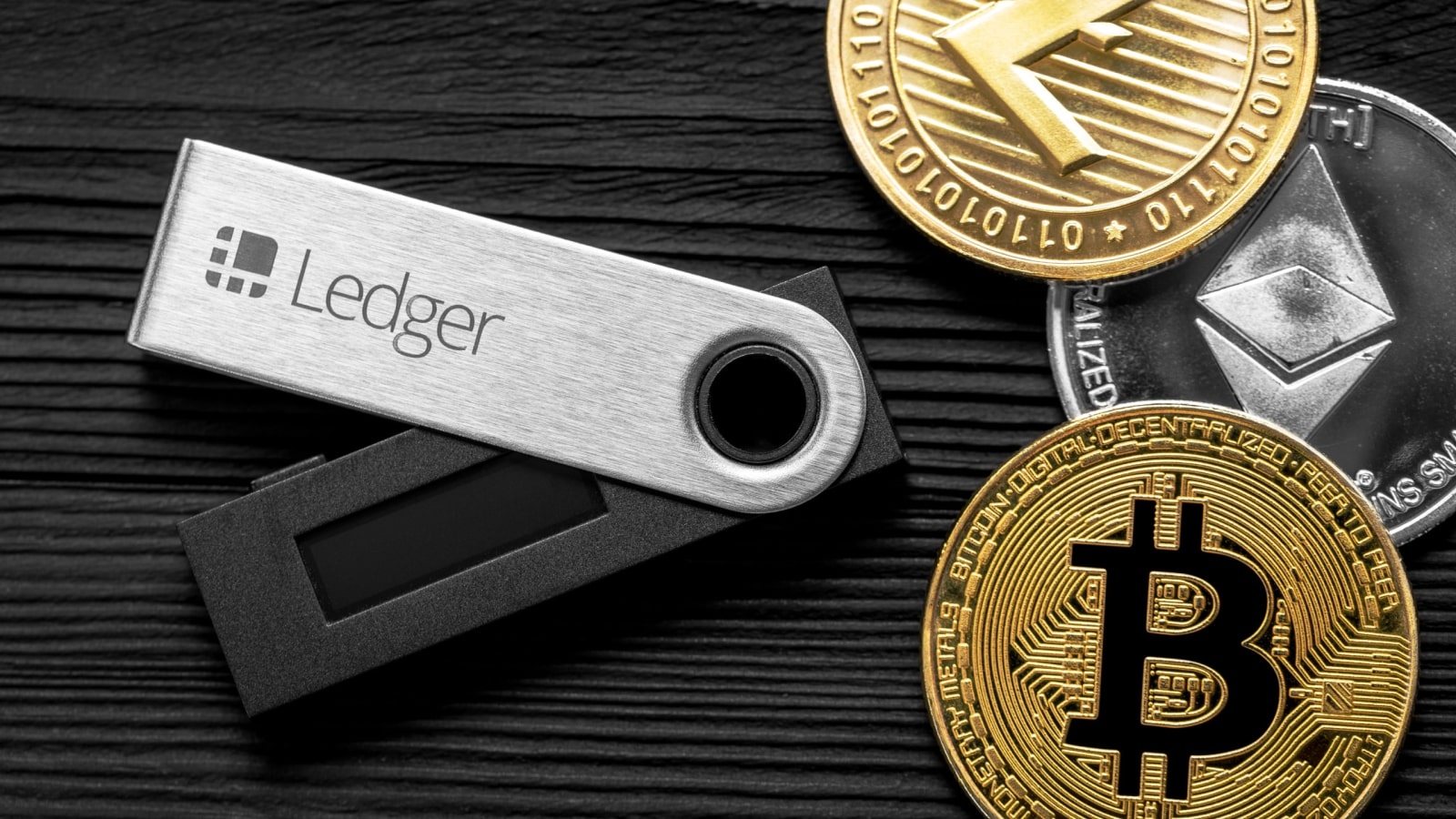 Hardware wallet on a dark desk next to a laptop